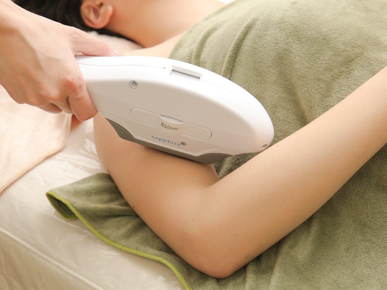 うつ伏せの状態で二の腕に脱毛機の光を当てているところ